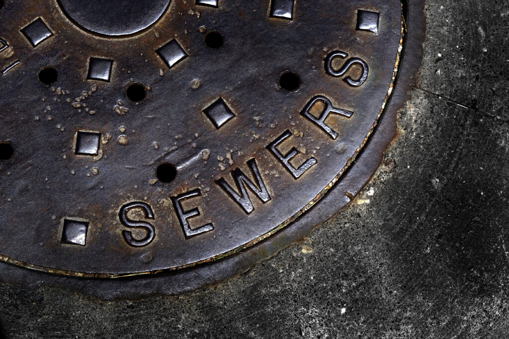 Man hole cover for sewer entry with iron grate on street in a city