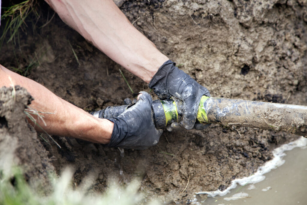 Hands on a sewer line in a yard