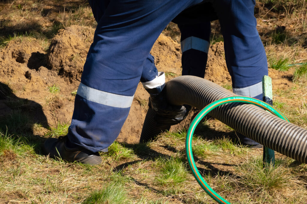 Man worker holding pipe, providing sewer cleaning service and a unclogging blocked manhole