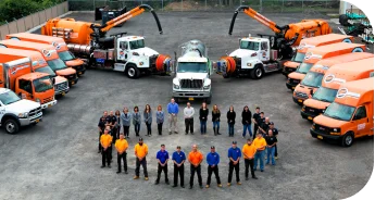 AP Plumbing team standing in a circle on black top in the middle of all the service vehicles